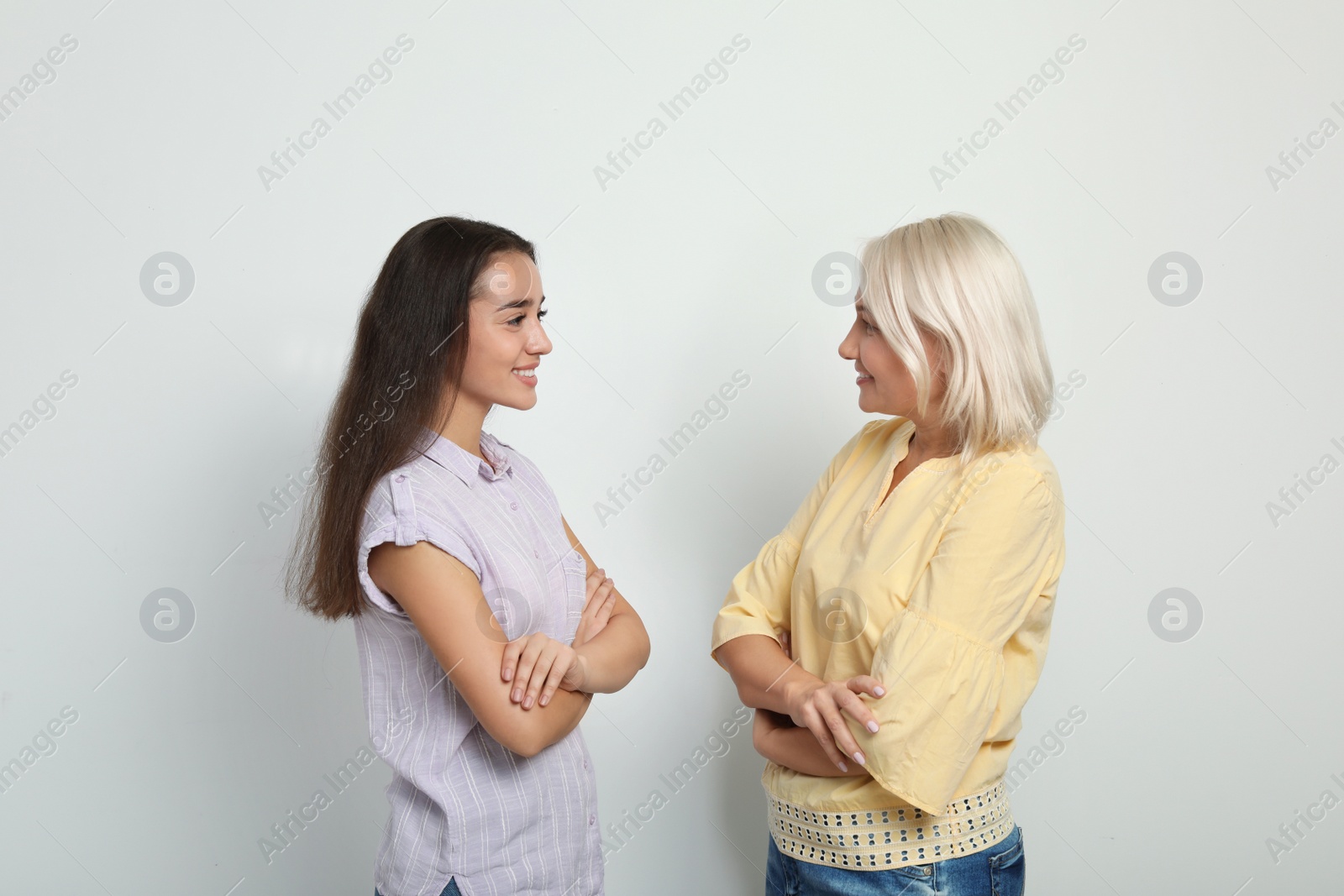 Photo of Portrait of young woman and her mother-in-law on white background. Happy family