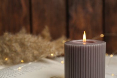 Burning candle on blurred background, closeup. Space for text