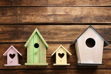 Photo of Collection of handmade bird houses on wooden background, flat lay. Space for text