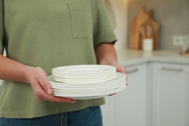 Woman holding plates in kitchen, closeup. Space for text