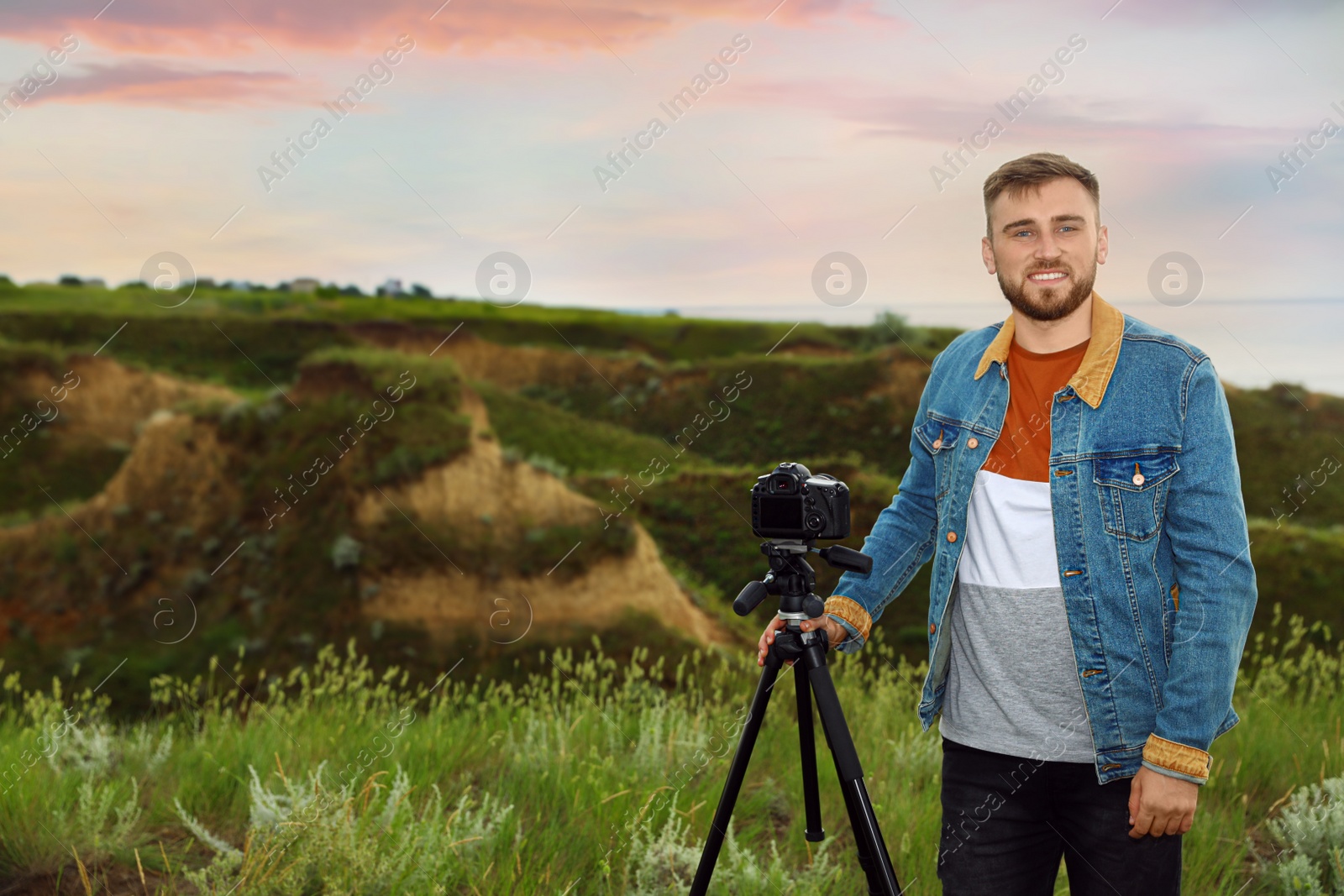 Photo of Male photographer with professional camera on green hill