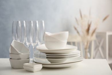 Set of clean dishware and champagne glasses on white table indoors