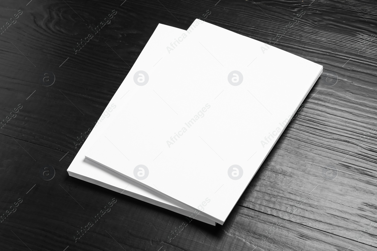 Photo of Stack of blank paper sheets for brochure on black wooden background. Mock up