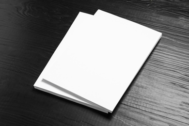 Stack of blank paper sheets for brochure on black wooden background. Mock up