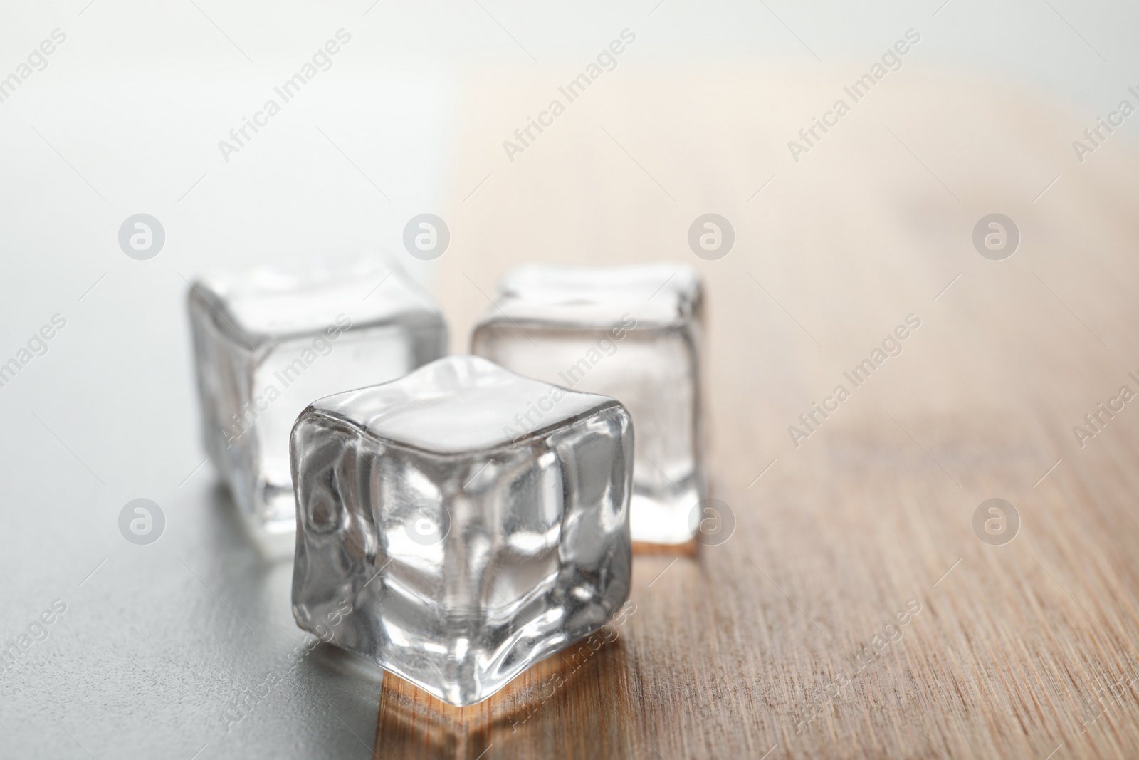 Photo of Crystal clear ice cubes on table, closeup. Space for text