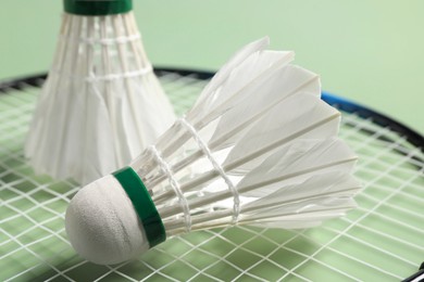 Feather badminton shuttlecocks and racket on green background, closeup