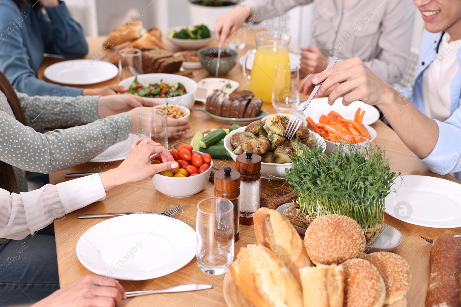 Photo of Friends eating vegetarian food at wooden table indoors, closeup