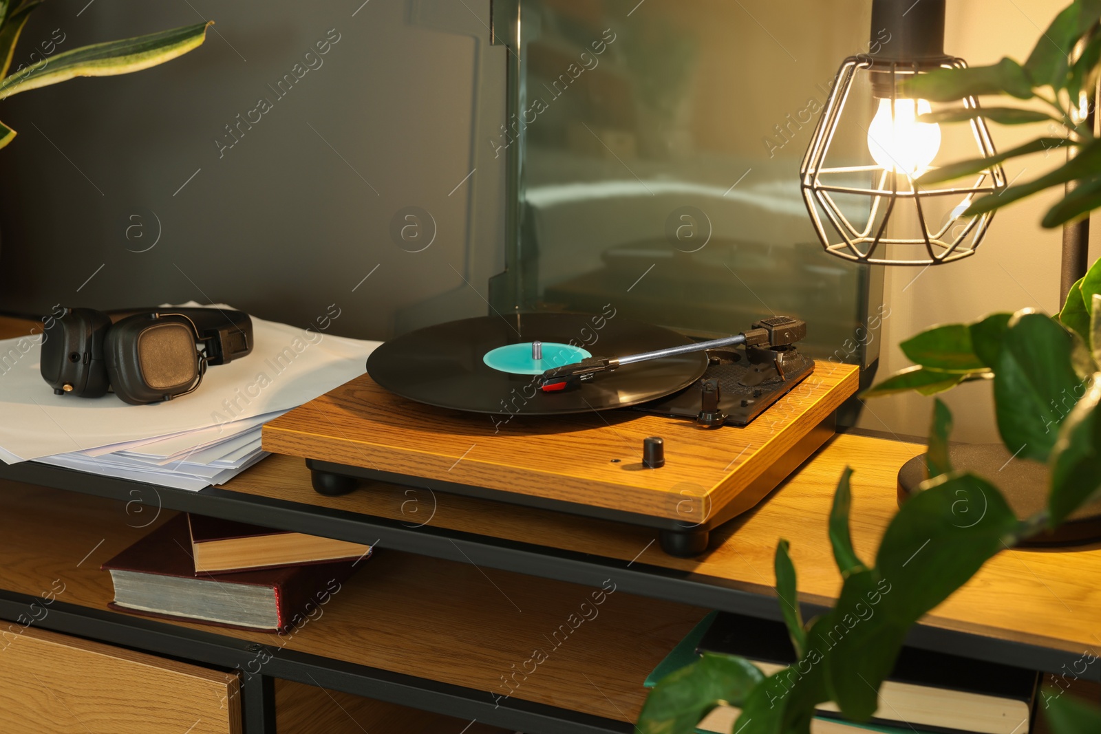 Photo of Stylish turntable with vinyl record on tv table indoors
