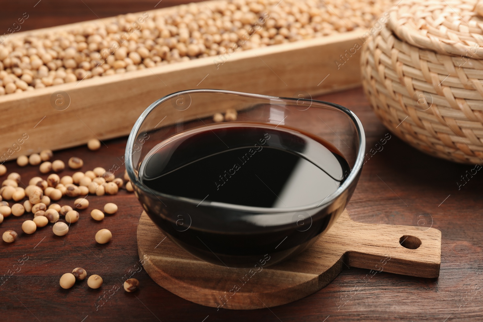 Photo of Soy sauce in bowl and soybeans on wooden table