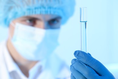 Photo of Scientist working with sample on light blue background, closeup. Medical research