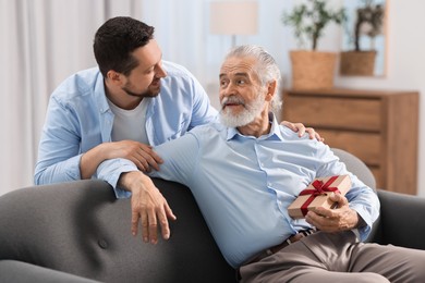 Photo of Son giving gift box to his dad at home