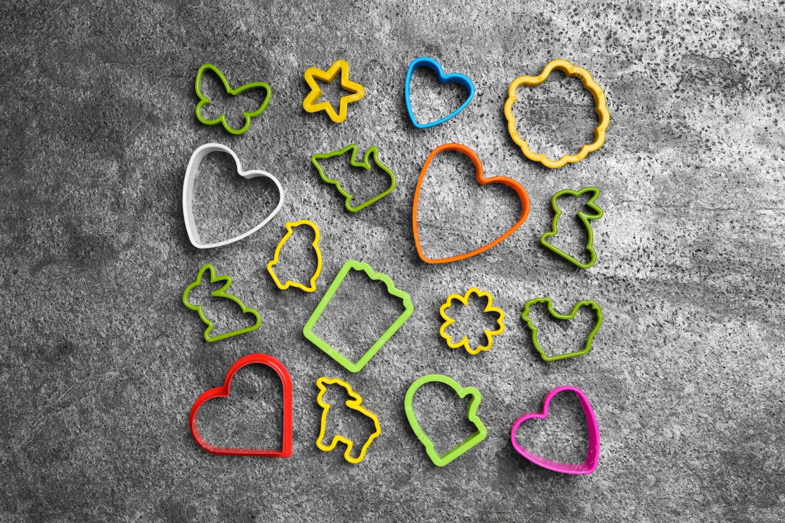 Photo of Set of different cookie cutters on grey table, flat lay. Cooking utensils