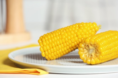 Photo of Plate with ripe corn cobs on table, closeup