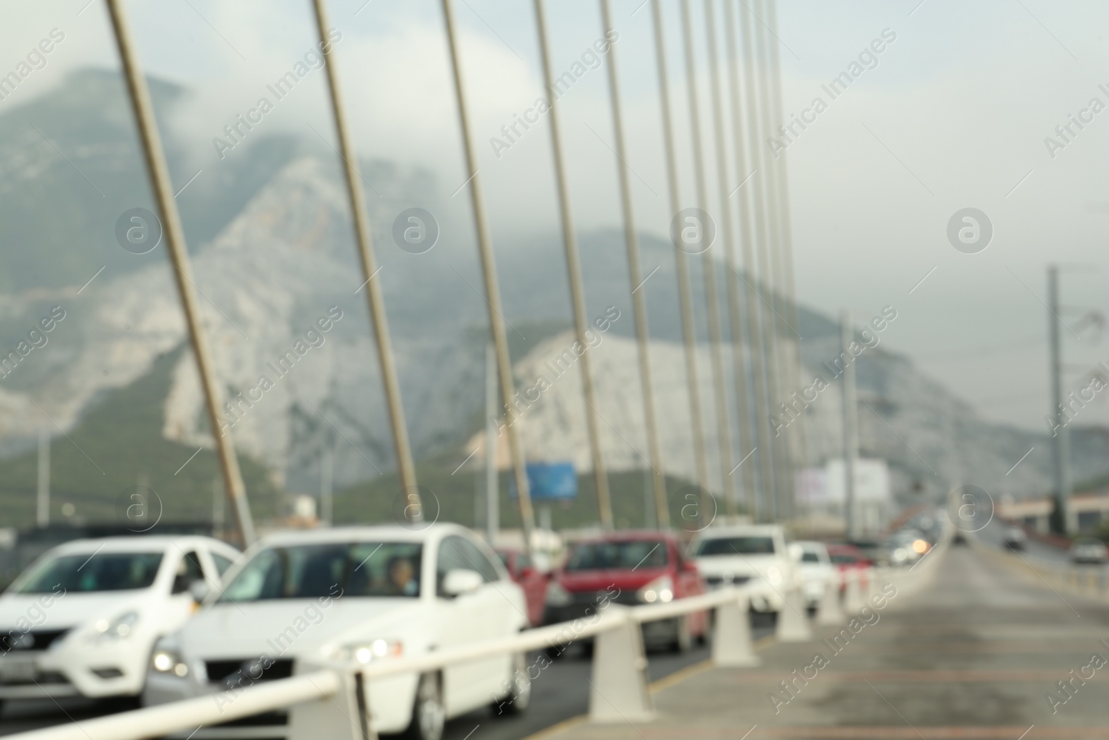 Photo of Blurred view of modern bridge and cars near mountain