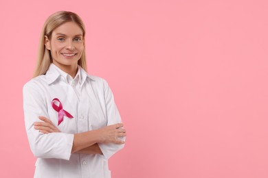 Photo of Doctor with pink ribbon on color background, space for text. Breast cancer awareness