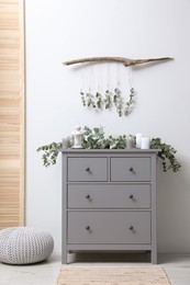Photo of Stylish room decorated with beautiful eucalyptus garland on chest of drawers
