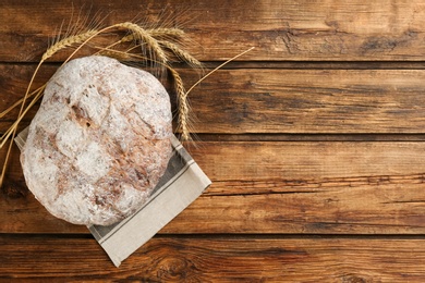 Photo of Tasty freshly baked bread and spikelets on wooden table, top view. Space for text
