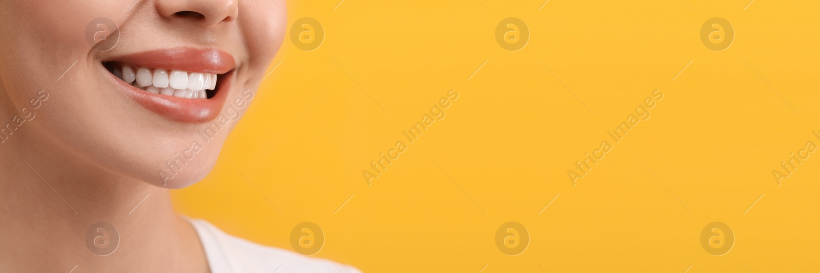 Image of Woman with clean teeth smiling on orange background, closeup. Banner design with space for text