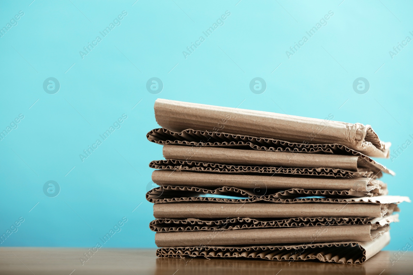 Photo of Stack of cardboard for recycling on table against color background. Space for text