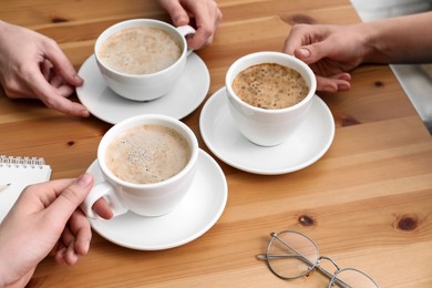 Women with cups of coffee at table in cafe, closeup