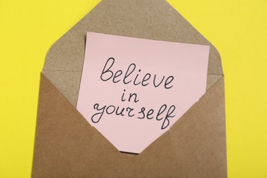 Photo of Envelope with message Believe In Yourself on yellow background, top view. Motivational quote