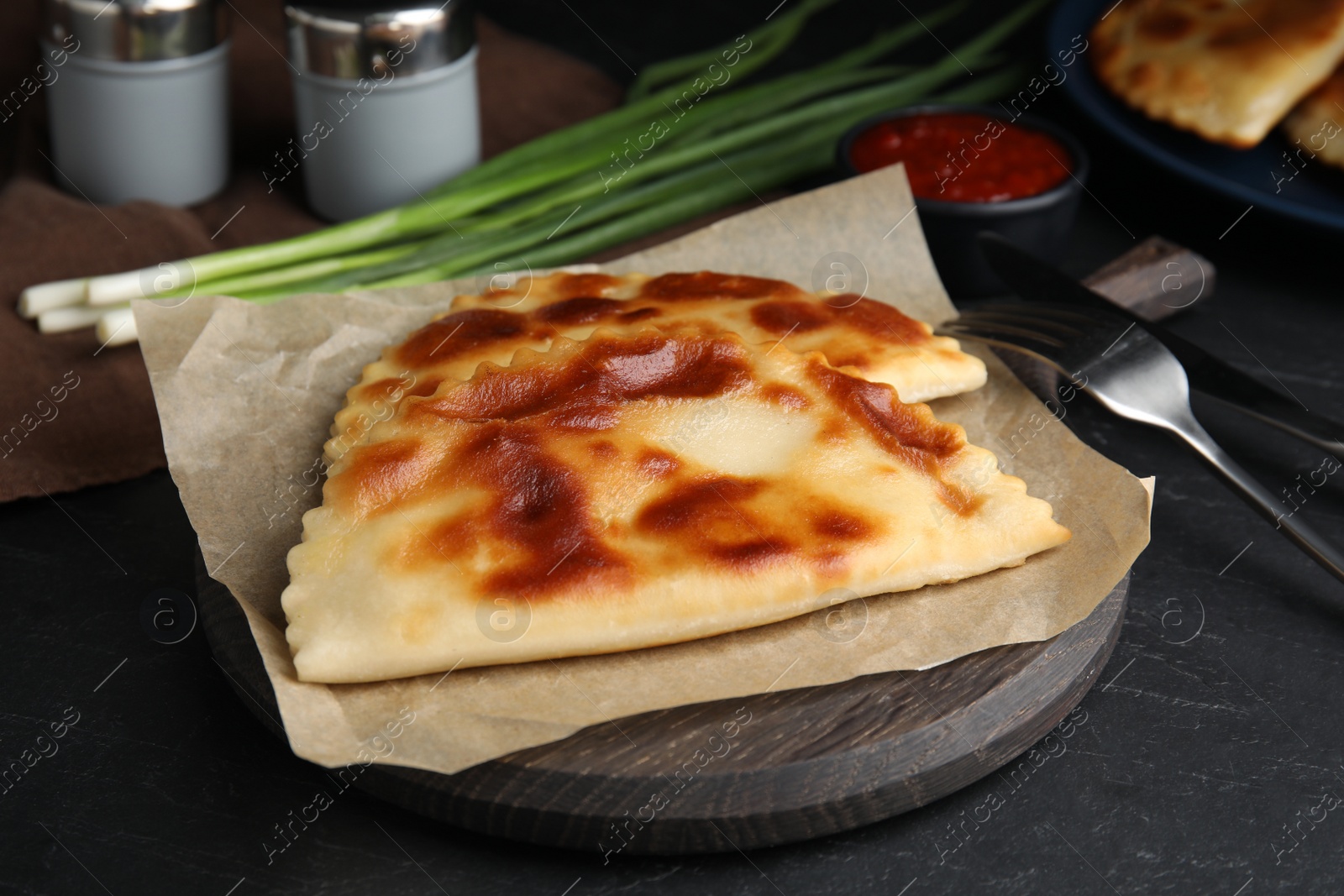 Photo of Delicious fried chebureki on black table. Traditional pastry