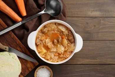 Tasty cabbage soup and ingredients on wooden table, flat lay. Space for text