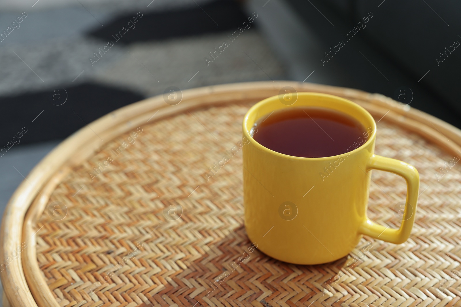 Photo of Ceramic mug of tea on wicker table indoors. Mockup for design