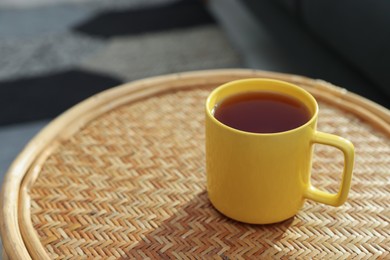 Photo of Ceramic mug of tea on wicker table indoors. Mockup for design