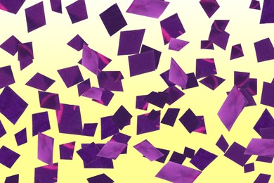 Image of Shiny purple confetti falling on gradient yellow background