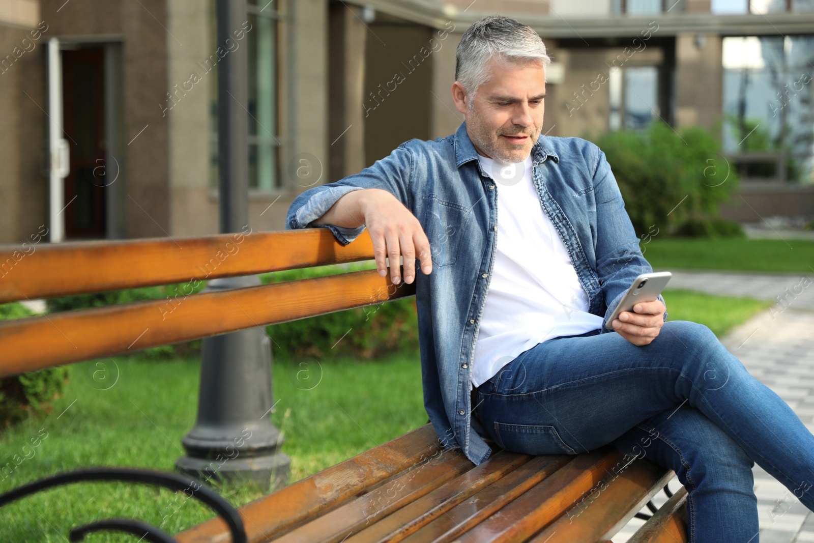 Photo of Portrait of handsome mature man using mobile phone in city. Space for text