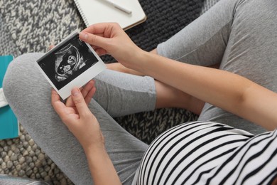 Photo of Pregnant woman holding ultrasound photo of baby, top view