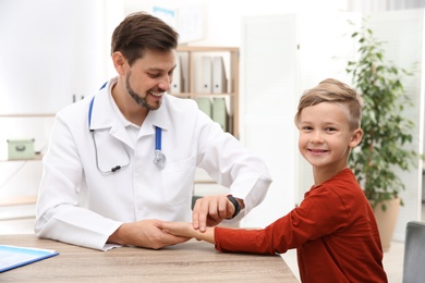 Doctor checking little boy's pulse with fingers in hospital