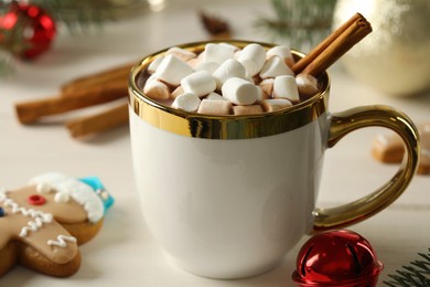 Delicious hot chocolate with marshmallows and cinnamon on white wooden table, closeup