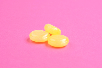 Photo of Tasty lemon flavored drops on pink background