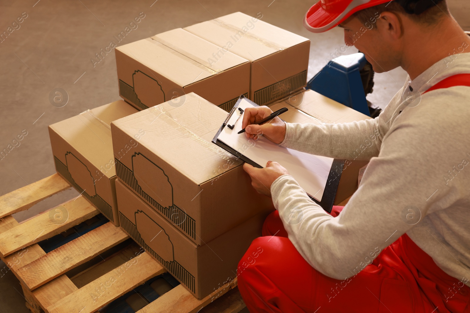 Image of Worker holding clipboard near pallet with boxes