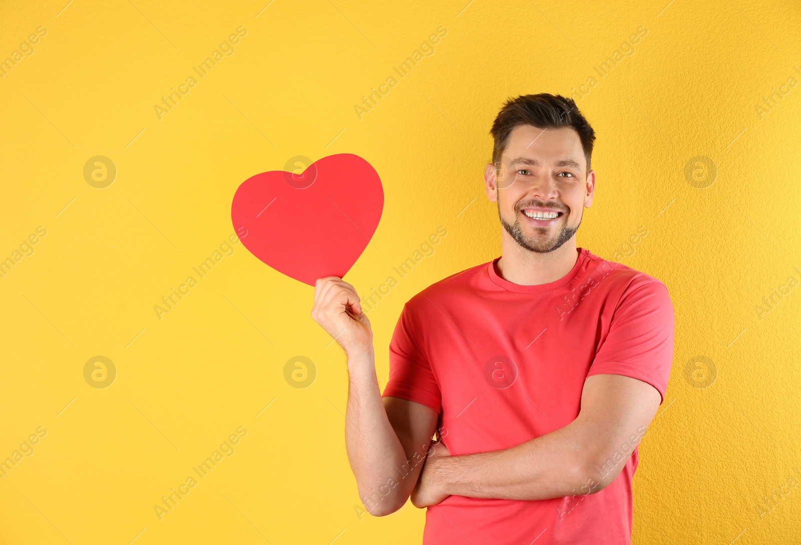 Photo of Portrait of handsome man with decorative heart on color background, space for text