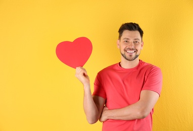 Portrait of handsome man with decorative heart on color background, space for text