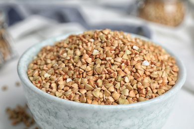 Bowl with organic green buckwheat on table, closeup view