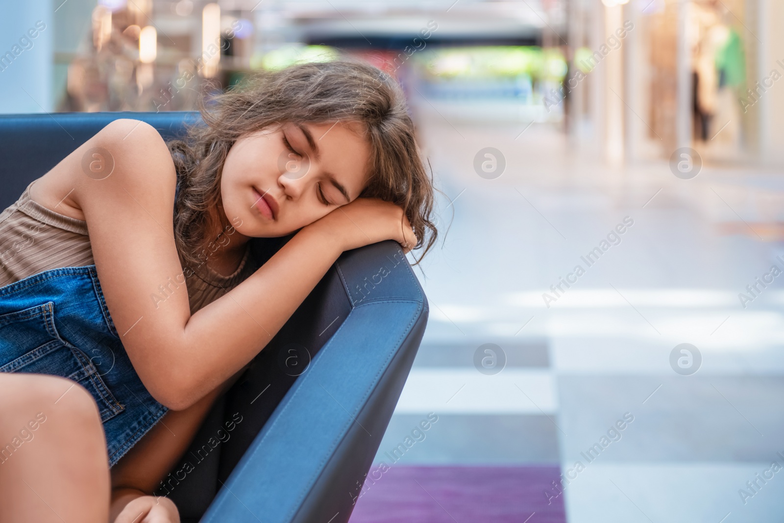 Photo of Tired teenage girl sleeping on sofa in shopping mall