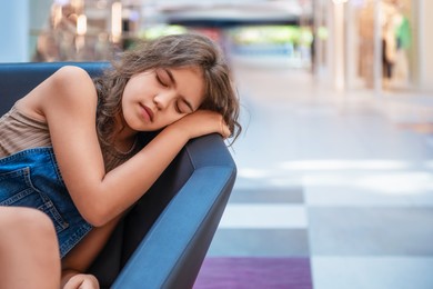 Photo of Tired teenage girl sleeping on sofa in shopping mall