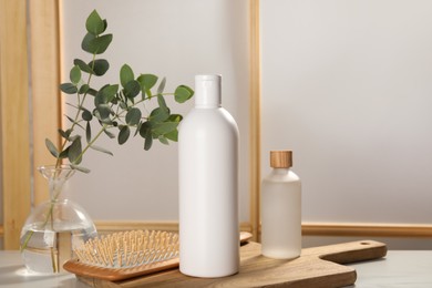 Photo of Bottles of shampoo and hairbrush on white table