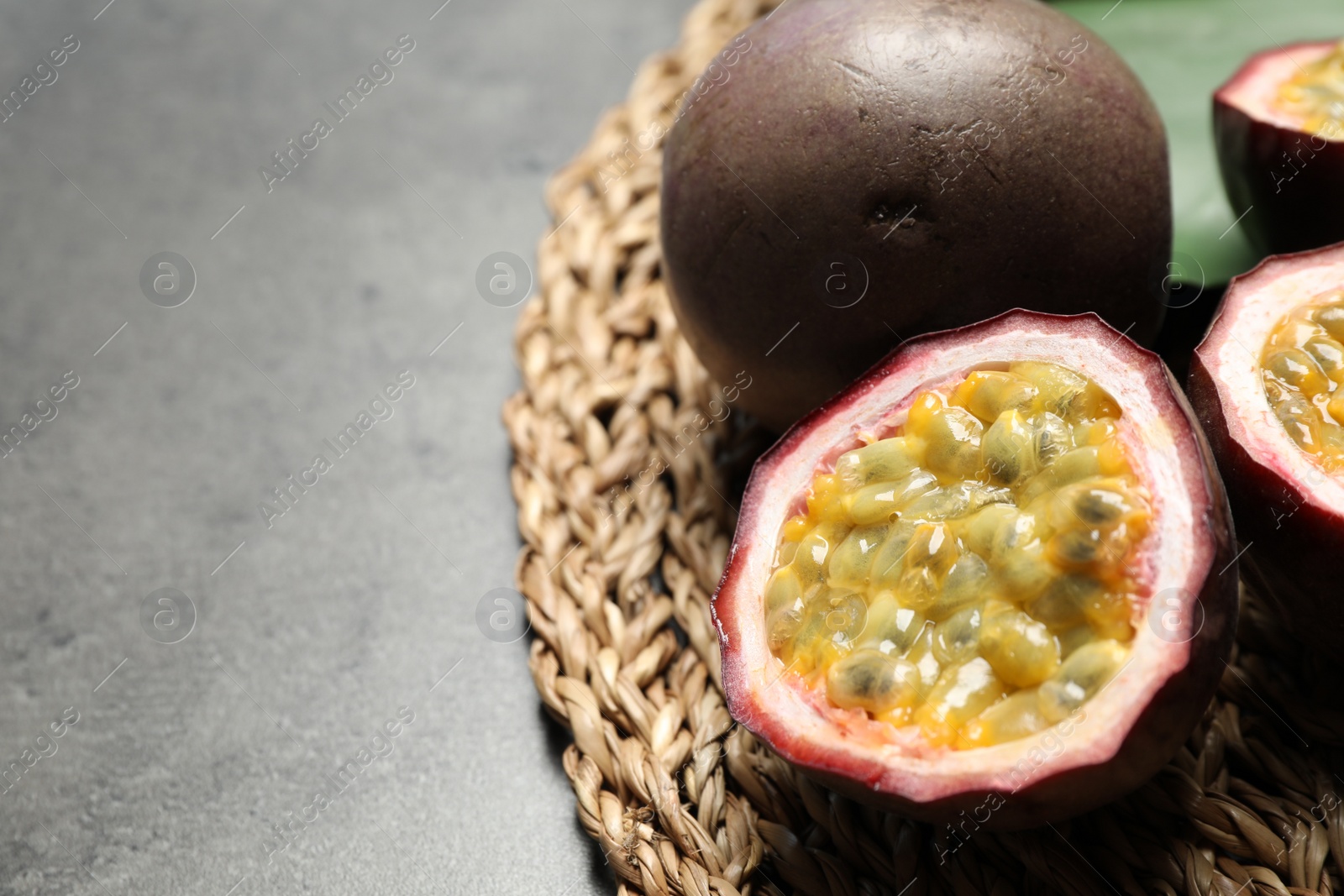 Photo of Cut and whole passion fruits (maracuyas) on grey table, closeup. Space for text