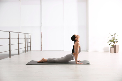 Photo of Young woman practicing cobra asana in yoga studio. Bhujangasana pose