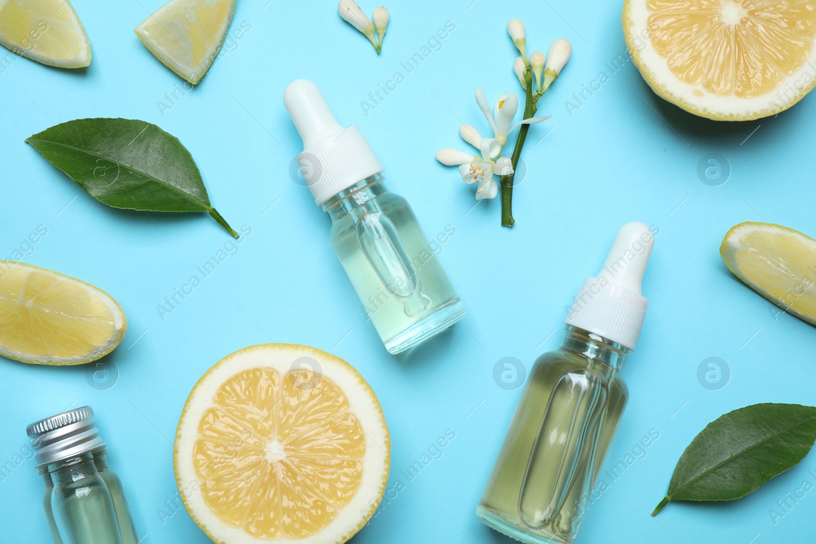 Photo of Flat lay composition with bottles of citrus essential oil on light blue background