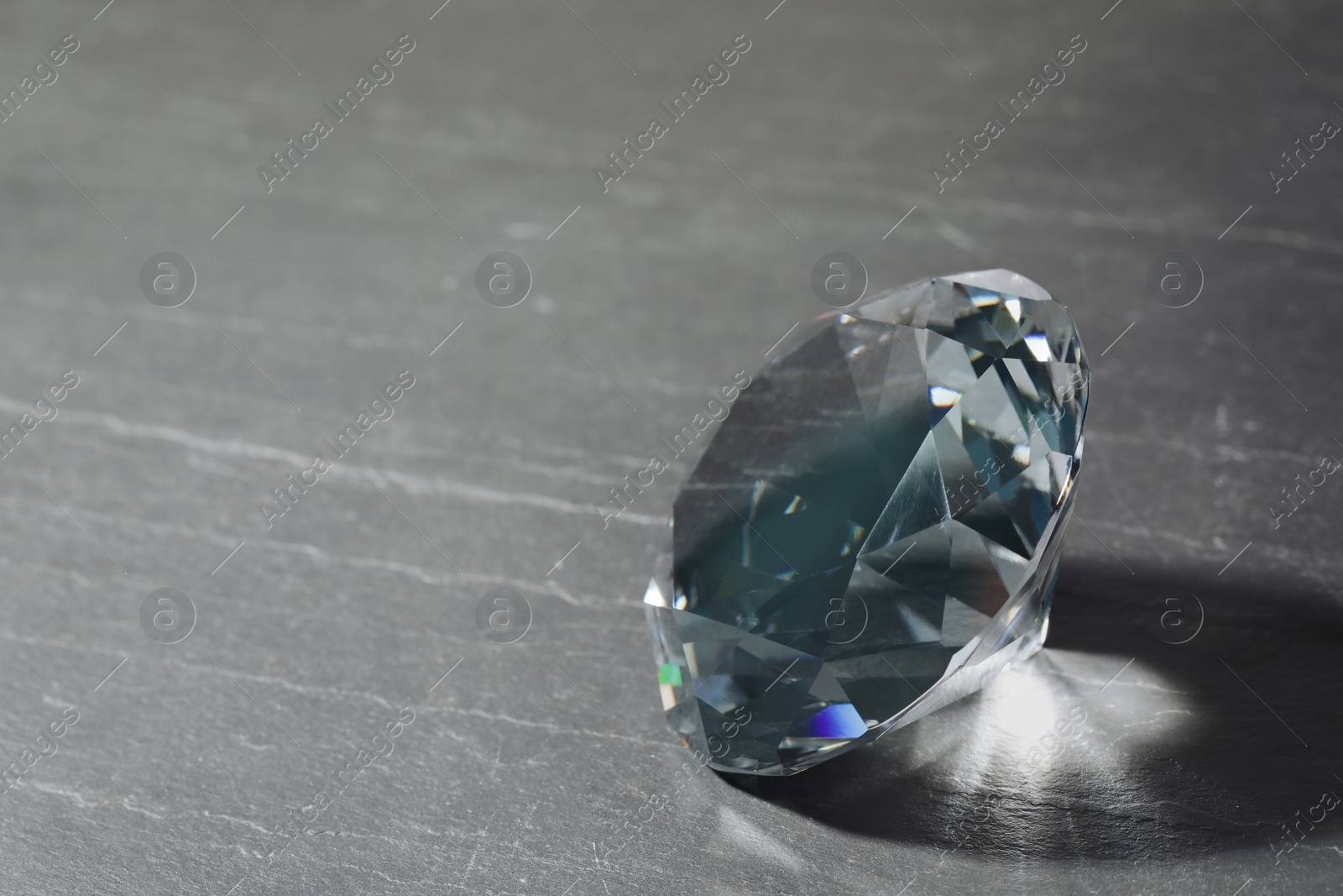 Photo of Beautiful dazzling diamond on black textured background, closeup. Space for text