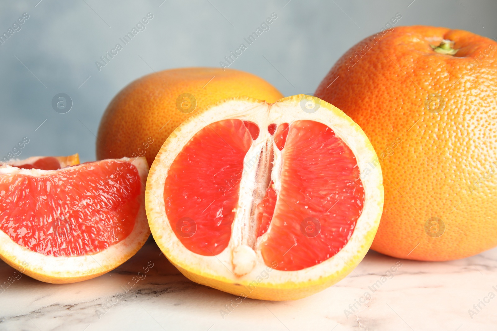 Photo of Whole and sliced tasty grapefruits on marble table