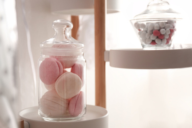 Tasty macarons and candies in glass jars indoors