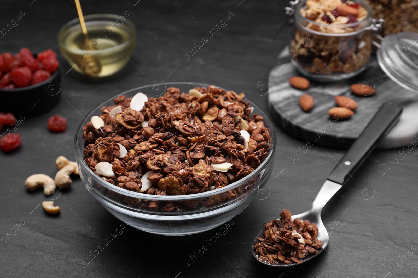 Photo of Tasty granola served with nuts and dry fruits on black table