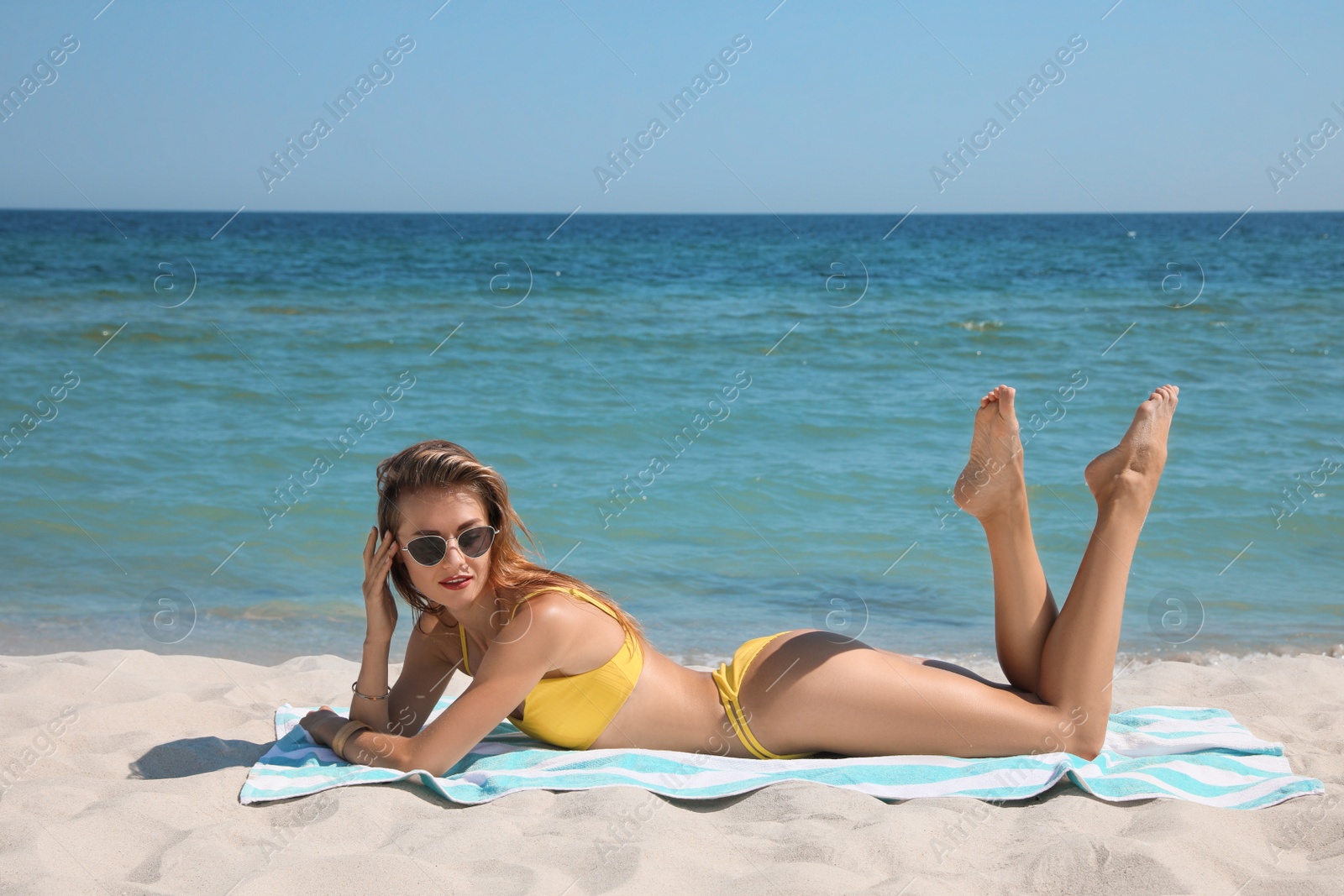 Photo of Beautiful woman with beach towel on sand near sea